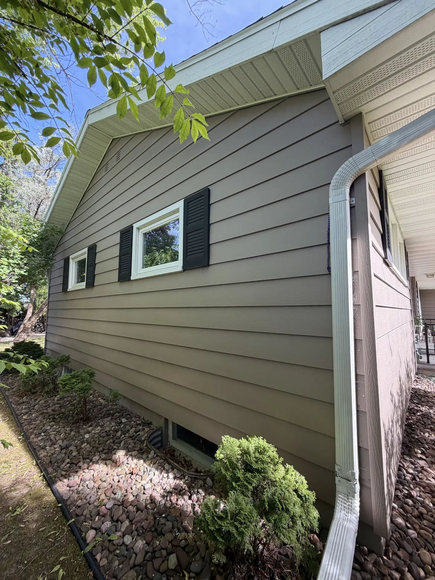 A finished exterior repaint in warm tan with a soft green trim line