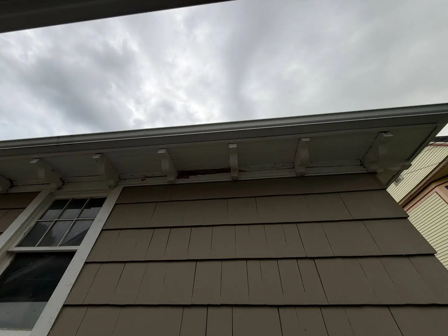 The same eave at the corner, where two runs meet and water sits longest.