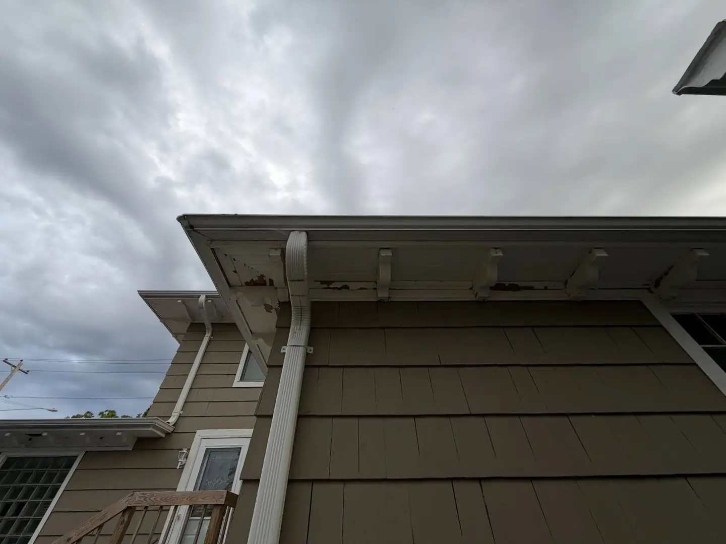 Fascia and soffit with the paint gone and the boards starting to come apart at the brackets.